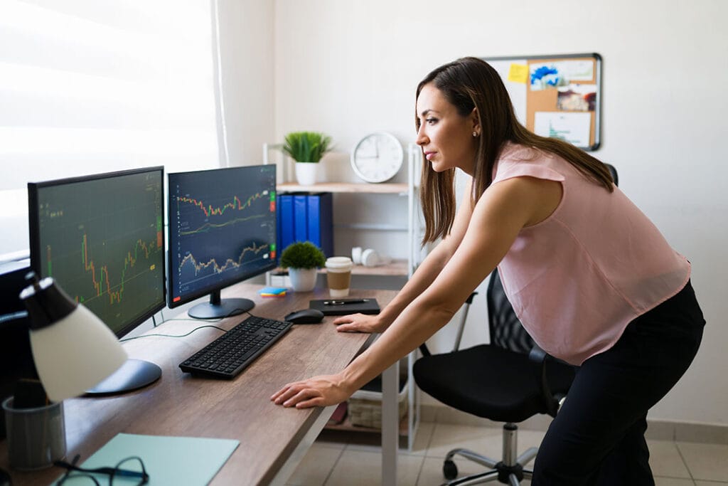 A trader looks at Forex graphs on her monitors.