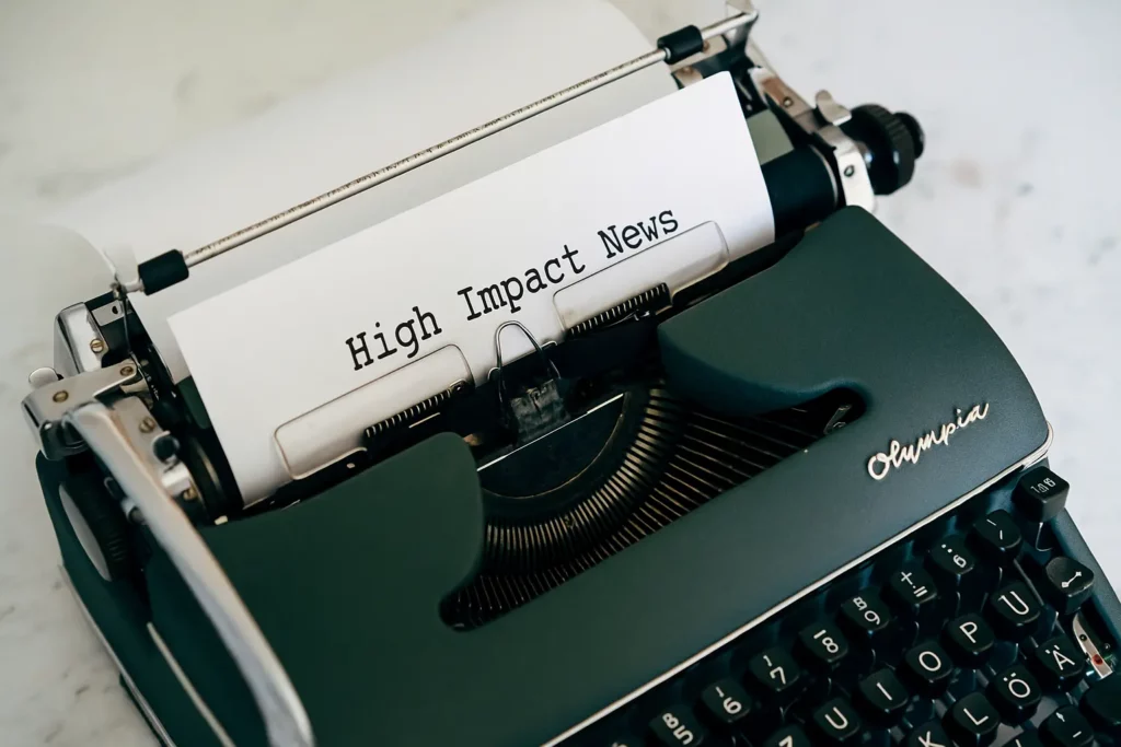 A vintage Olympia typewriter with a sheet of paper inserted, displaying the text "High Impact News" in black typewriter font, centered on the page representing CPI news.