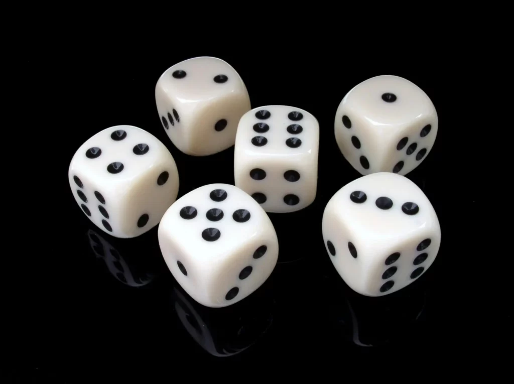 Five white six-sided dice with black pips on a reflective black surface.