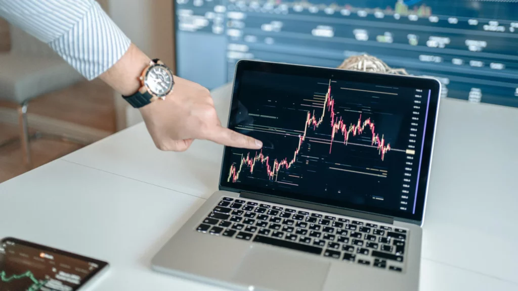 Hand pointing to trading chart on laptop, illustrating prop firm trading mistakes from scattered focus. 