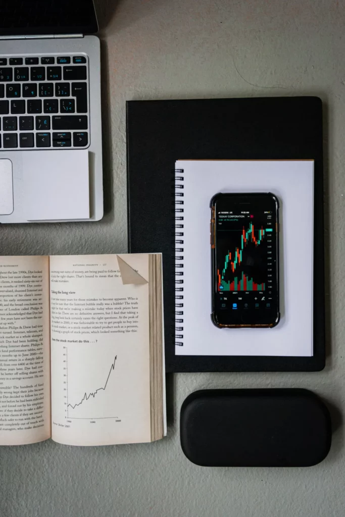 Open books, laptop, notebook and smartphone with financial charts for learning how prediction markets work.