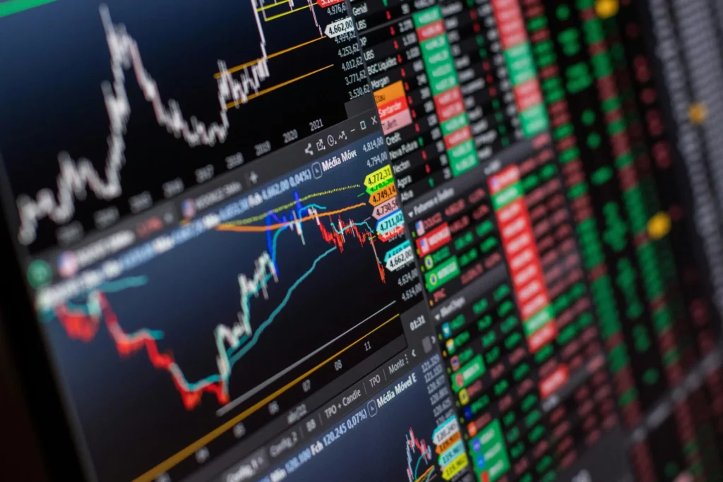 Prediction Markets vs Sports Betting: Close-up of real-time financial trading charts and market data on multiple screens. 