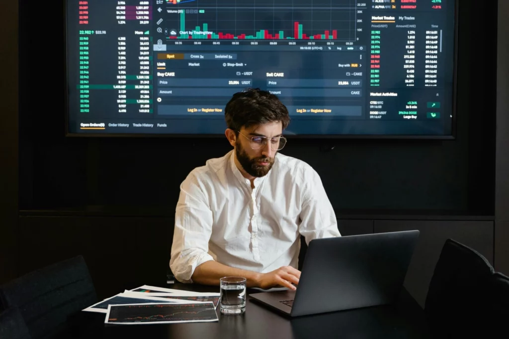 Prediction Markets vs Sports Betting: Focused trader analyzing real-time charts and market data on a large monitor and laptop. 