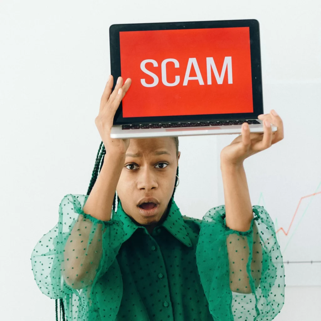 Prop firm myths - Shocked woman holding laptop with 'SCAM' on screen, representing the common myth that prop firms are scams.